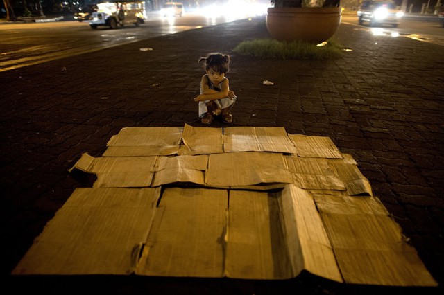 Cô bé 5 tuổi chuẩn bị giường ngủ làm từ những tấm bìa giấy trên một con phố ở Manila, Philippines vào đêm Giáng sinh.