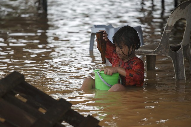 Một bé gái chơi trên đường phố bị ngập lụt ở vùng ngoại ô của Kota Bharu, Malaysia.