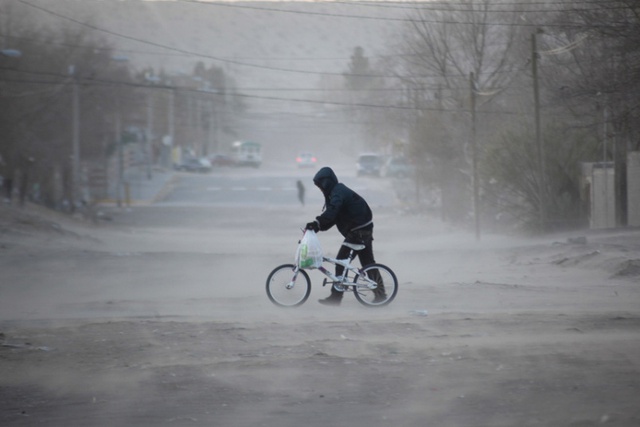 Người đàn ông dắt xe đạp qua đường trong gió lạnh tại vùng Ciudad Juarez, Mexico.
