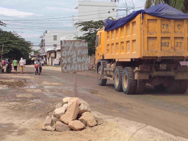 Bức ảnh này được chụp lại vào tháng 7 vừa qua. Theo phản ảnh của người dân địa phương, thì thời điểm đó các xe tải chở đất san lấp mặt bằng các dự án trên đường Phong Châu, TP. Nha Trang chạy liên tục suốt ngày đêm và đã tàn phá nghiêm trọng con đường, khiến nhà dân 2 bên đường rung lắc mạnh mỗi khi có xe qua. Vì quá bức xúc trước việc này, người dân ở đây đã cắm biển trên đường với nội dung lạy các ông nội xe chạy chậm lại. 