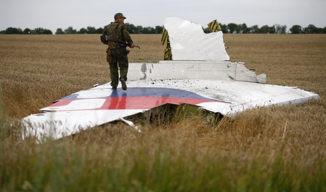Một binh sĩ thuộc lực lượng ly khai thân Nga đứng trên mảnh vỡ của chiếc máy bay Boeing 777 xấu số