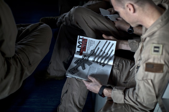 
Một phi công trên tàu chăm chú đọc quyển tạp chí về các loại vũ khí.

