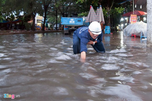 Ông Đặng Văn Kỳ (51 tuổi), công nhân công ty thoát nước dùng tay không moi rác thải trên miệng cống để nước nhanh rút. Ảnh: Zing.vn