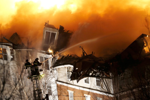 Lính cứu hỏa đứng trên thang phun nước để dập tắt đám cháy bùng phát tại một khu chung cư ở Edgewater, bang New Jersey, Mỹ.