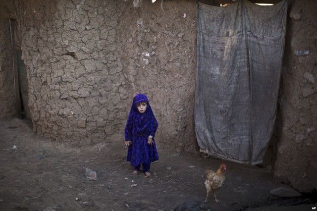 Bé gái tị nạn người Afghanistan đứng bên ngoài ngồi nhà bằng bùn của gia đình mình tại một khu ổ chuột ở Islamabad, Pakistan.
