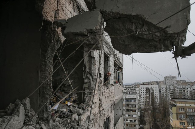 Người dân nhìn qua cửa sổ một tòa nhà chung cư bị phá hủy trong đợt pháo kích vào thành phố Donetsk, Ukraine.