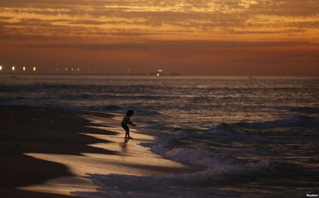 Bé gái Palestine chơi trên bãi biển lúc hoàng hôn tại thành phố Gaza.