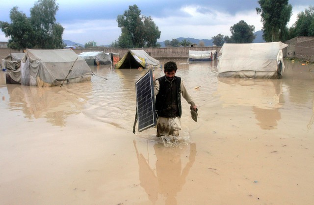 Người đàn ông đi qua nước ngập lụt ở Behsud, Afghanistan.