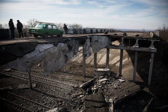 Xe ô tô đi qua cây cầu bị phá hủy một phần ở thị trấn Debaltseve, Ukraine.