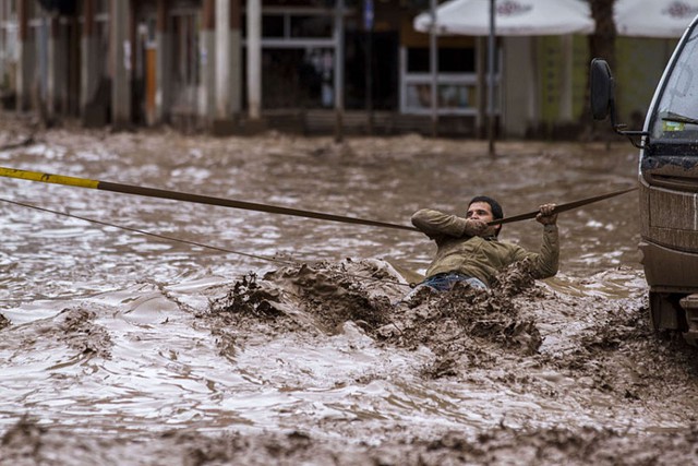 Người đàn ông phải đu dây để vượt qua đoạn đường ngập lụt đầy bùn đất ở thành phố Copiapo, Chile.