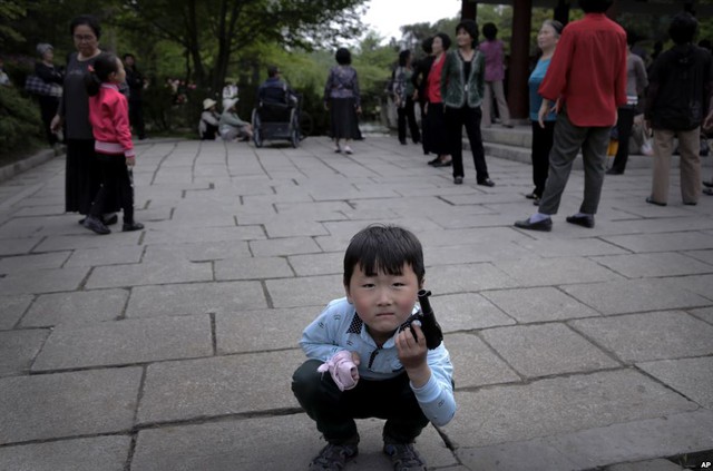 Em bé Triều Tiên chơi với súng nhựa khi mọi người tập trung tại một ban công trên đồi Moran ở thủ đô Bình Nhưỡng.