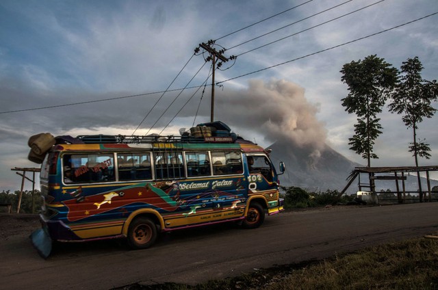 Xe bus chạy qua núi lửa Sinabung đang phun trào tro bụi tại huyện Karo ở tỉnh North Sumatra, Indonesia.