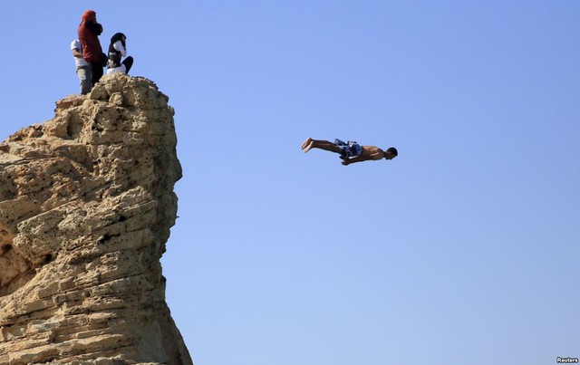 Nam thanh niên nhảy từ mỏm đá xuống biển để tắm mát trong một ngày nắng nóng ở thành phố Marsa Matrouh, Ai Cập.