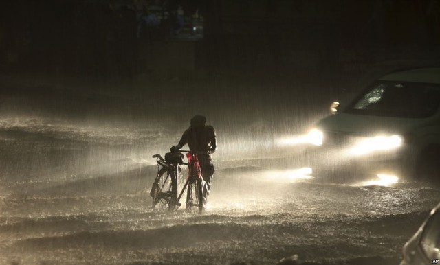 Người đàn ông dắt xe đạp trên đường phố ngập nước do mưa lớn tại thành phố Jammu, Ấn Độ.