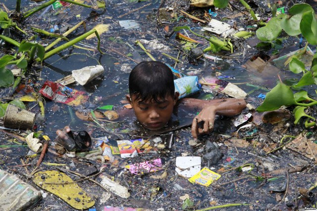 Cậu bé thu lượm những đồ có thể tái chế dưới một dòng sông gần thành phố Navotas, Philippines.