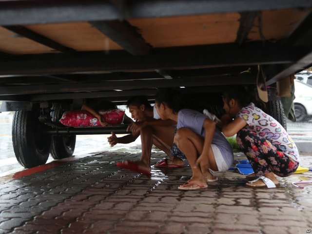 Người dân trú mưa dưới gầm một chiếc xe container khi cơn bão Linfa đang hướng về thủ đô Manila, Philippines.