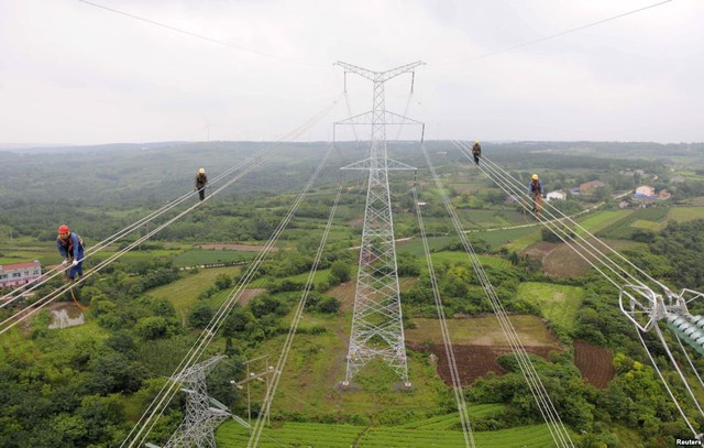 Công nhân đi dọc dây điện khi họ kiểm tra lưới điện cáo thế chạy qua cánh đồng ở thành phố Trừ Châu, Trung Quốc.