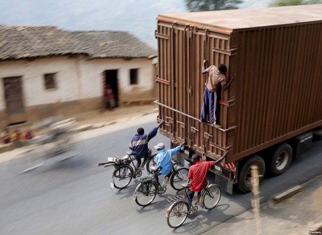 Những người đi xe đạp bám vào sau một chiếc xe container ở ngoại ô thủ đô Bujumbura, Burundi.