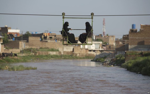 Những người phụ nữ ngồi trên xe tời để vượt một dòng suốt trong mùa nước lũ ở Rawalpindi, Pakistan.
