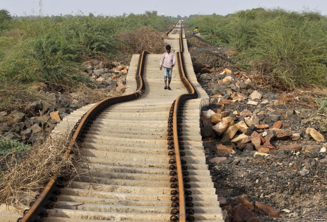 Một người dân đi bộ trên đường ray tàu hỏa bị hư hại sau nhiều ngày mưa lớn tại thành phố Gujarat, Ấn Độ.