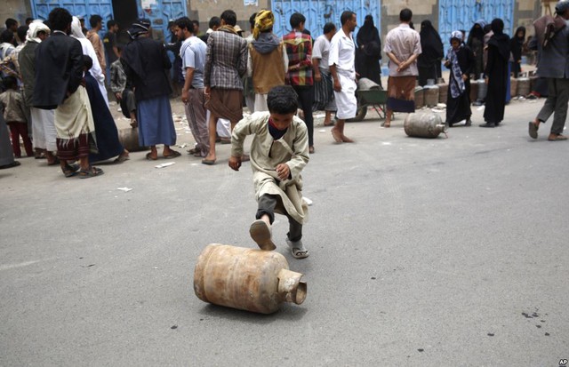 Cậu bé lăn bình ga mới mua được sau khi phải xếp hàng nhiều giờ ở Sanaa, Yemen.