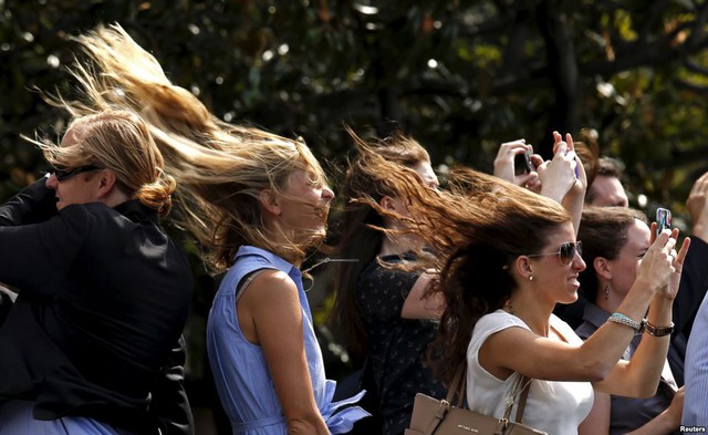 Các cô gái bị gió thổi bay tóc khi đứng xem chuyên cơ Marine One chở Tổng thống Mỹ Barack Obama cất cánh rời khỏi Nhà Trắng.