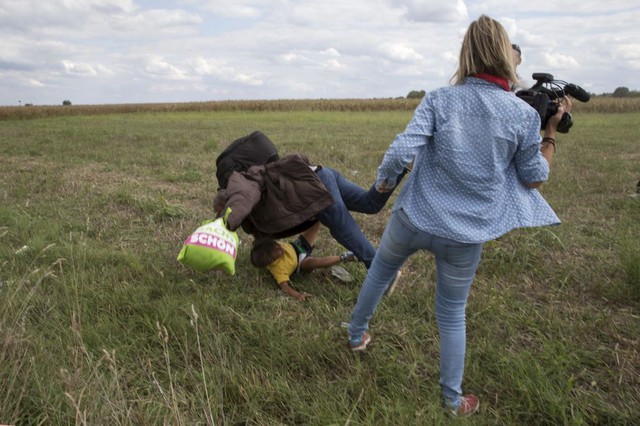Người di cư bế con ngã xuống đất sau khi bị nữ phóng viên ngáng chân trong khi cố gắng thoát khỏi trại tị nạn ở ngôi làng Roszke, Hungary.