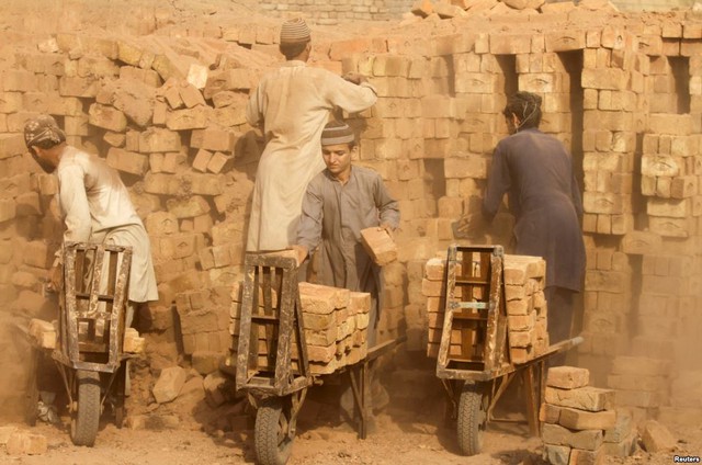 Công nhân vận chuyển gạch nung khỏi một lò đốt ở ngoại ô thành phố Peshawar, Pakistan.