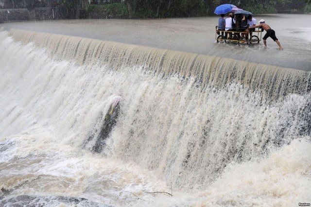 Người dân di chuyển qua một đập tràn dưới mưa lớn gây ra bởi siêu bão Koppu ở thành phố Las Pinas, Philippines.