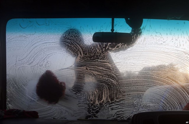 Cậu bé lau rửa kính chắn gió ô tô tại một điểm rửa xe ở thành phố Dhaka, Bangladesh.