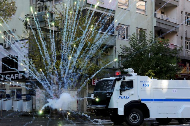 Cảnh sát chống bạo động phun vòi rồng trong khi người biểu tình ném pháo tự chế đáp trả tại thành phố Diyarbakir, Thổ Nhĩ Kỳ.