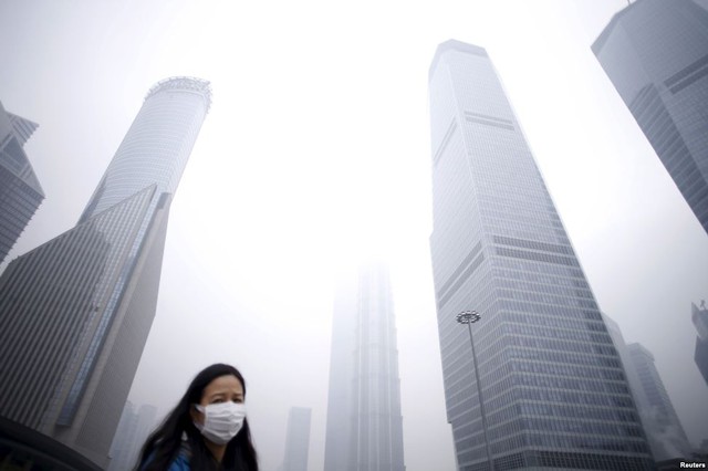 
Một phụ nữ đeo khẩu trang đi dưới những tòa nhà chọc trời giữa không khí ô nhiễm ở thành phố Thượng Hải, Trung Quốc.
