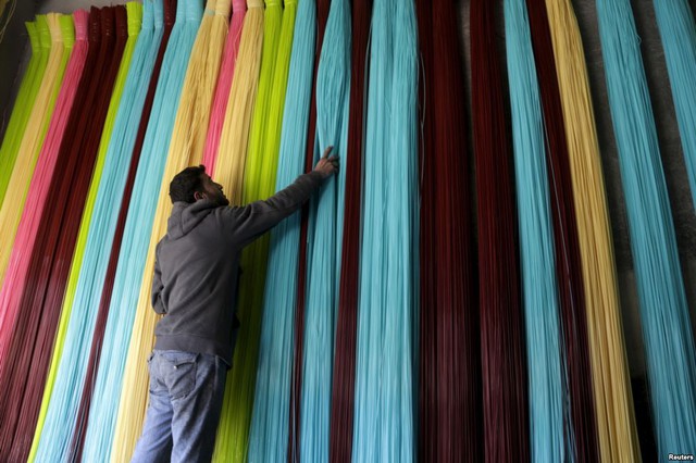 Người đàn ông chỉnh những sợi nhựa được sử dụng để sản xuất thảm tại một nhà máy do quân nổi dậy kiểm soát ở thị trấn Maarshureen, Syria.
