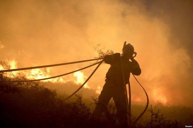Lính cứu hỏa thu vòi dẫn nước trong khi chiến đấu với cháy rừng gần thị trấn Berango ở Tây Ban Nha.