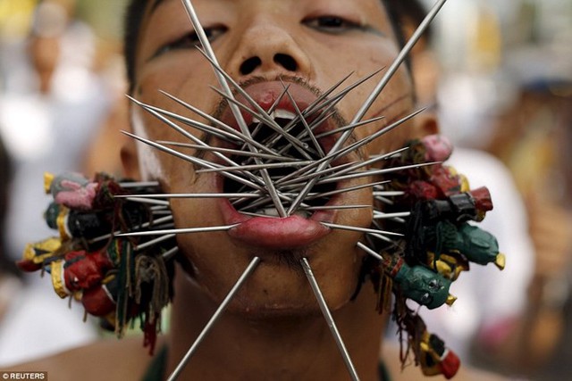 Hàng trăm người đàn ông Thái Lan đã đâm những chiếc que nhọn, những lưỡi dao lớn và thậm chí là cả nòng súng qua hai bên má, nhằm ăn mừng lễ hội ăn chay hàng năm của người dân nước này. (Nguồn: Reuters)