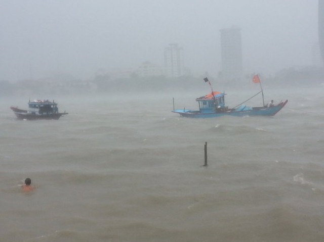 
Tàu thuyền neo đậu trên sông Hàn bị sóng nước đánh mạnh, nhiều người dân đang cố gắng kéo vào bờ - Ảnh: PHAN THÀNH/Tuổi trẻ
