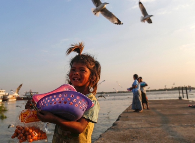 Bé gái bán thức ăn dành cho chim mòng biển tại cầu tàu Botahtaung ở Rangoon, Myanmar.