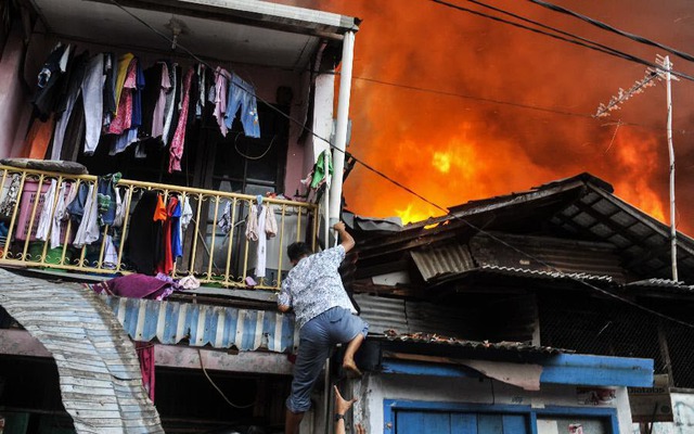 Người dân trèo xuống từ tầng 2 nhà của mình trong một vụ hỏa hoạn ở Tanah Abang, Jakarta, Indonesia.