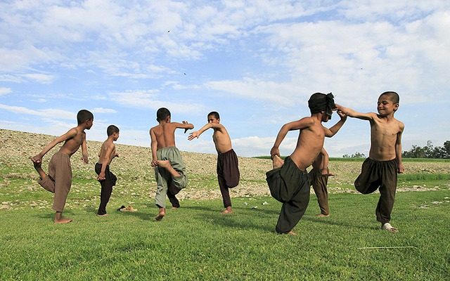 Trẻ em cởi trần chơi đùa với nhau trên bãi cỏ ở ngoại ô Jalalabad, Afghanistan.