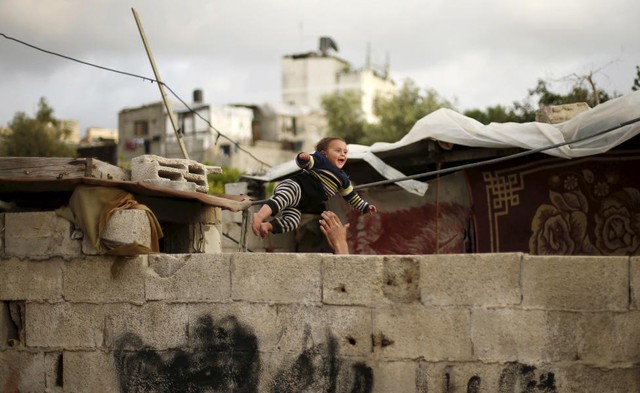 Người đàn ông Palestine chơi với con trai nhỏ bên ngoài ngôi nhà bị tàn phá bởi bom đạn ở thị trấn Biet Lahiya, Dải Gaza.