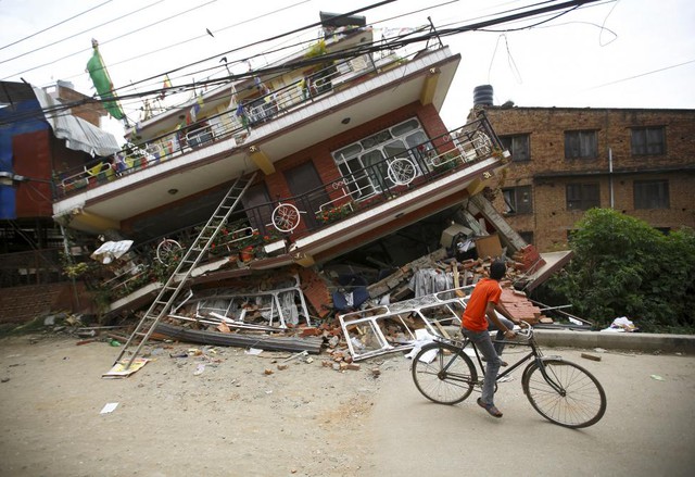 Cậu bé đạp xe qua ngôi ngôi nhà bị phá hủy trong trận động đất tại Kathmandu, Nepal.
