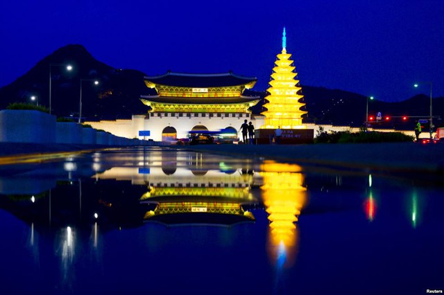 Cặp đôi đi trước cung điện Gyeongbokgung được chiếu sáng rực rỡ tại Seoul, Hàn Quốc.