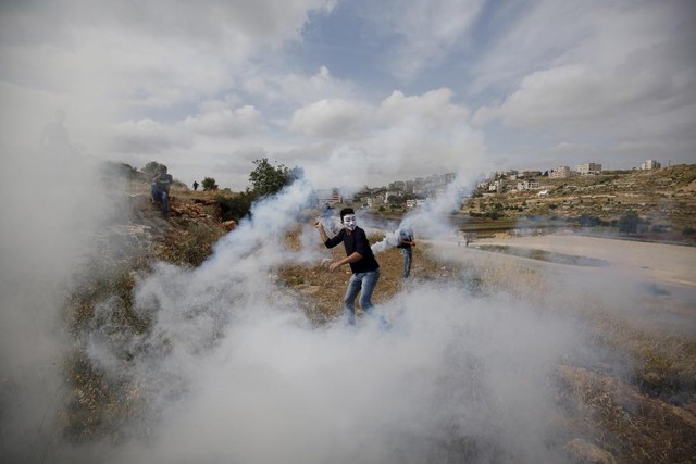 Người biểu tình Palestine ném đạn hơi cay trả lại quân đội Israel tại thành phố Ramallah, Bờ Tây.