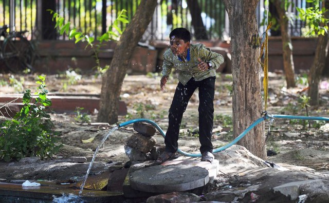 Cậu bé rừa mặt với vòi nước trong một ngày nắng nóng tại New Delhi, Ấn Độ.