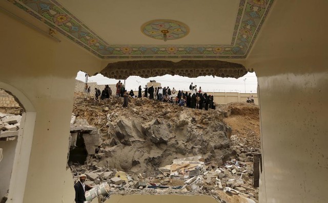 Mọi người nhìn đống đổ nát của những ngôi nhà bị phá hủy trong đợt không kích của liên quân Ả-rập vào thành phố Sanaa, Yemen.