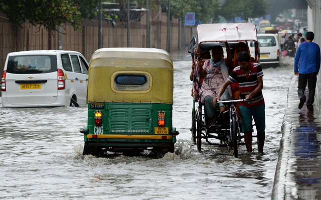 Các phương tiện di chuyển khó khăn trên đường phố ngập lụt tại thành phố New Delhi, Ấn Độ.