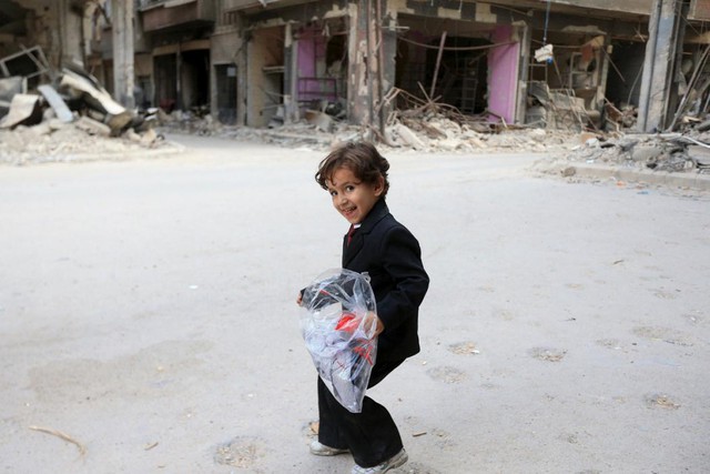 Một cậu bé vui sướng cầm túi quần áo mới khi Syria ăn mừng việc kết thúc tháng ăn chay Ramadan.