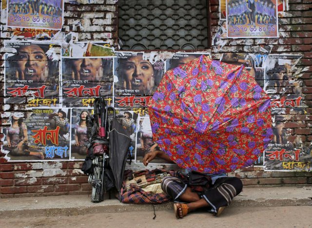 Một người làm nghề sửa ô ngồi trên vỉa hè tại thành phố Dhaka, Bangladesh.