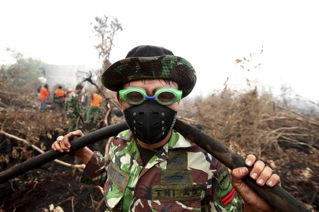 Một người lính sử dụng kính bơi để bảo vệ mắt khỏi khói khi đang hỗ trợ chữa cháy trong một khu rừng ở Parit Indah, Indonesia.