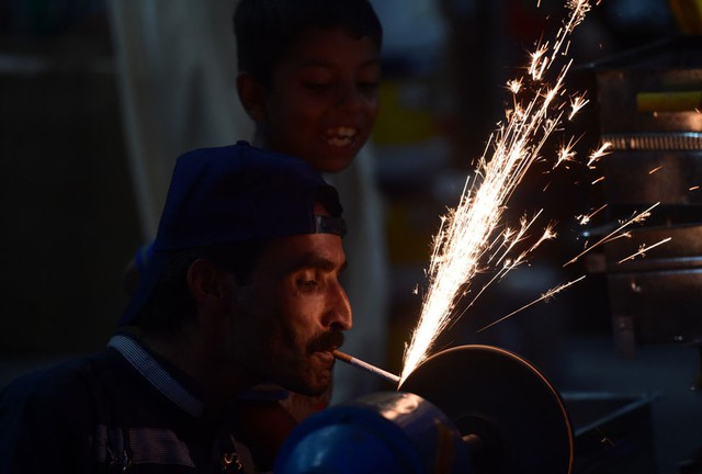 Người thợ vừa châm thuốc lá vừa mài dao cho lễ Eid al-Adha hàng năm ở Rawalpindi, Pakistan.